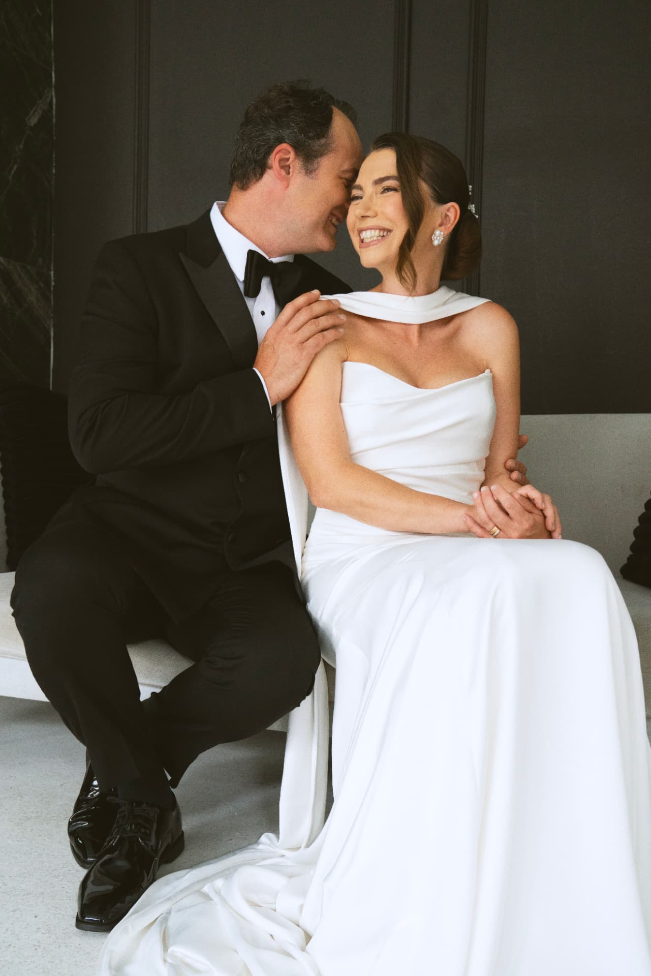 Couple complice et souriant, robe blanche et smoking, lors de leur séance anniversaire de mariage